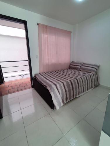 a bedroom with a bed and a large window at Apartaestudio Colibrí in Buga