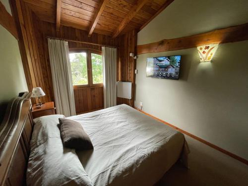 a bedroom with a bed and a tv on the wall at Villa del Lago in San Carlos de Bariloche