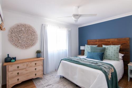 um quarto com uma cama e uma parede azul em Time and Tide 1 em Tuncurry