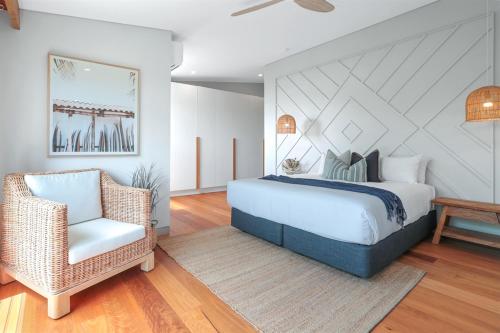 a bedroom with a large bed and a chair at Luxe Coastal Abode, Marcus Beach in Marcus Beach