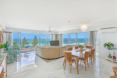 a living room with a couch and a table and chairs at Solnamara Beachfront Apartments in Gold Coast