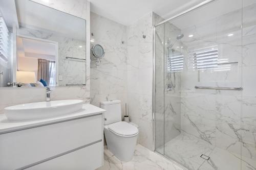 a white bathroom with a toilet and a shower at Solnamara Beachfront Apartments in Gold Coast