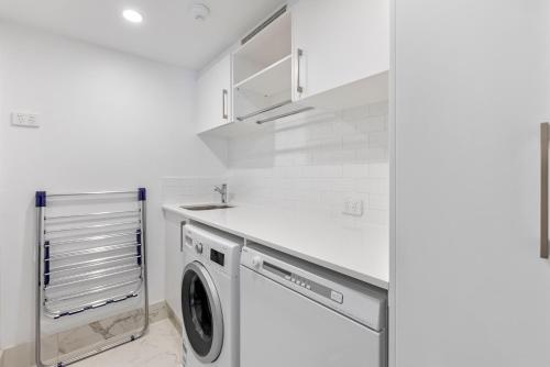 a white laundry room with a washer and dryer at Solnamara Beachfront Apartments in Gold Coast