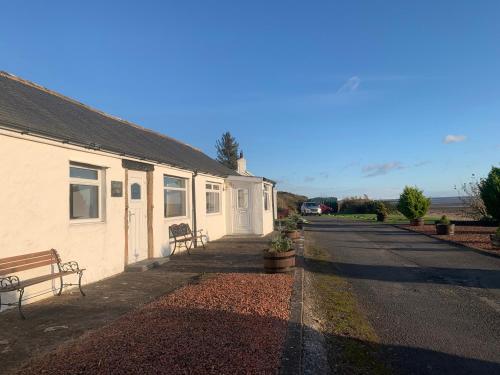 a building with a bench next to a street at Solway Firth View in Annan