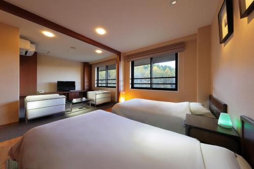 a hotel room with two beds and a desk at Hotel Ryu Resort and Spa in Takayama