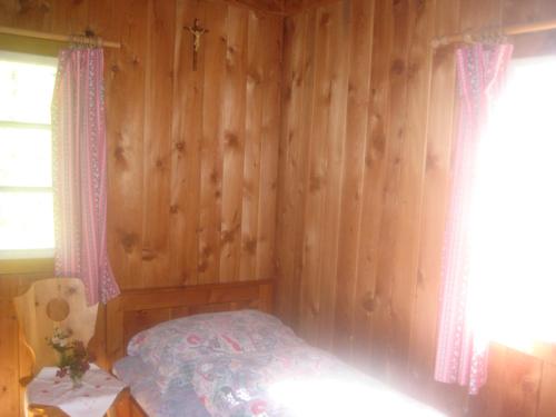 a bedroom with a bed and a wooden wall at Almhütte Gorgasser in Heiligenblut