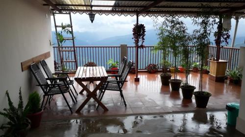 Un patio con una mesa y sillas en un balcón. en The River View Homestay, en Kurseong