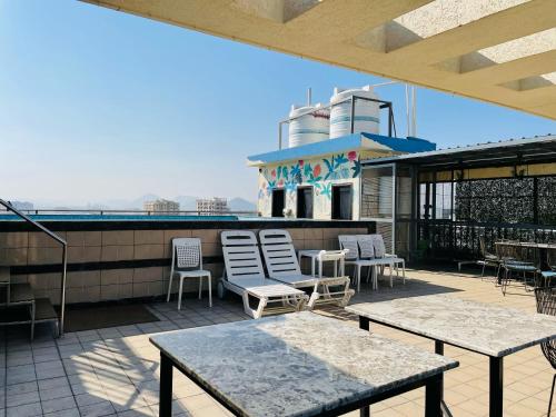 a patio with chairs and tables on a roof at Clover Inn in Udaipur