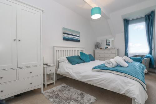 a bedroom with a bed with blue pillows on it at Headland Apt 17 in Coverack