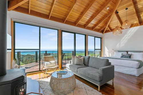 a living room with a couch and a bed and windows at Point of View Villas in Apollo Bay