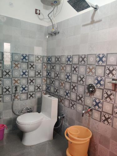 a bathroom with a toilet and a tiled wall at Rudransh home stay in Rishīkesh