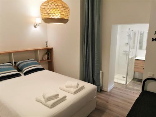 a bedroom with a white bed with two towels on it at VILLA Henry - FOCH in Les Sables-dʼOlonne