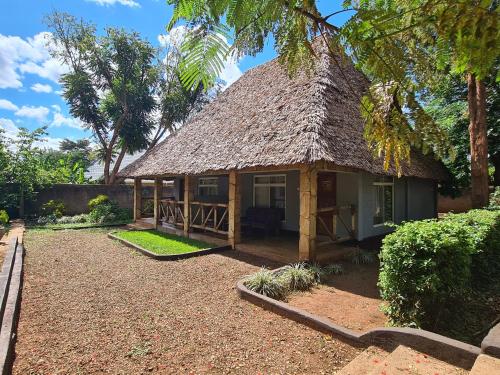 a small house with a thatched roof at Honey Badger Lodge in Moshi