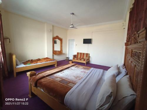 a bedroom with a large bed and a chair at FR Darya E Swat Hotel in Mingora