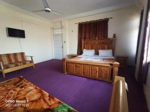 a bedroom with a large wooden bed and a couch at FR Darya E Swat Hotel in Mingora