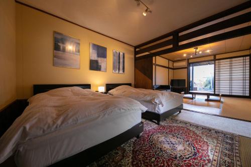 a bedroom with two beds and a rug at Yufuin Bath Satoyamasafu in Yufuin