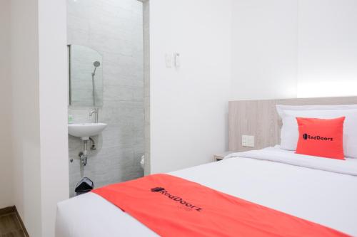 a bedroom with a bed with a red pillow and a sink at RedDoorz Plus @ Jalan Juanda Medan in Medan