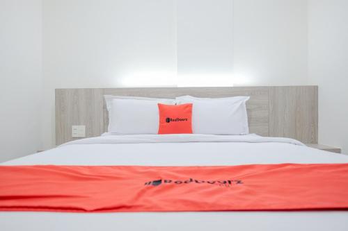 a bed with a red blanket and two pillows on it at RedDoorz Plus @ Jalan Juanda Medan in Medan