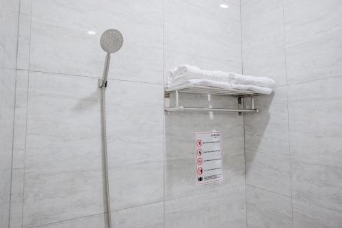 a shower in a bathroom with a sign on the wall at RedDoorz Plus @ Jalan Juanda Medan in Medan