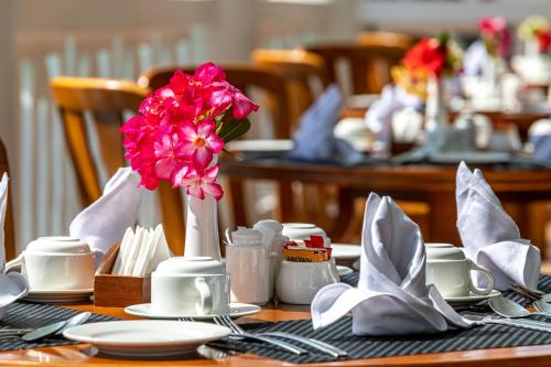 a table with a pink flower in a vase on it at PrideInn Flamingo Beach Resort & Spa Mombasa in Mombasa