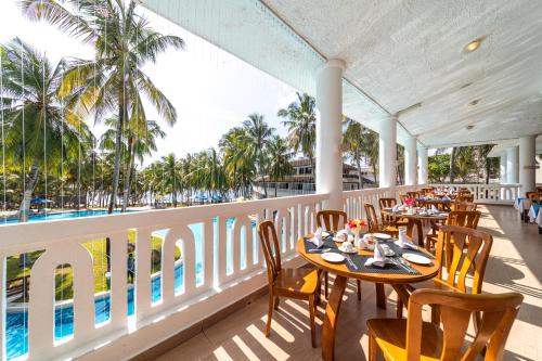 un restaurant avec des tables et des chaises sur un balcon dans l'établissement PrideInn Flamingo Beach Resort & Spa Mombasa, à Mombasa