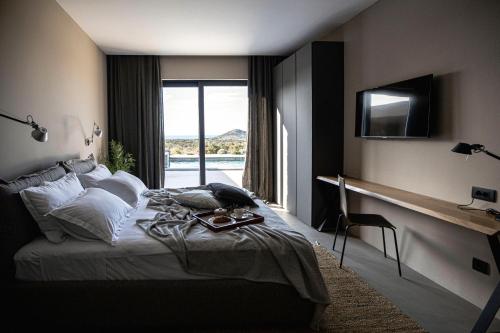 a bedroom with a bed with a television and a window at Villas Misto in Primošten