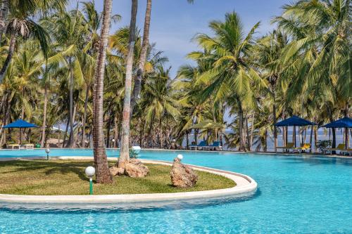 a pool at a resort with palm trees at PrideInn Flamingo Beach Resort & Spa Mombasa in Mombasa