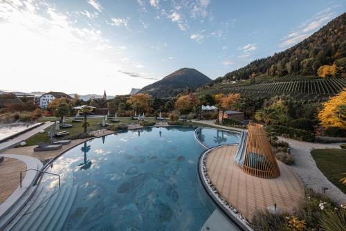a large swimming pool with a mountain in the background at ALPIANA - green luxury Dolce Vita Hotel in Vollan