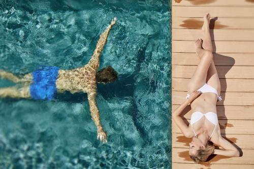two people are swimming in a swimming pool at ALPIANA - green luxury Dolce Vita Hotel in Vollan