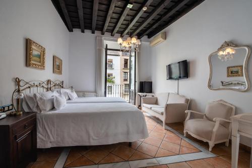 a bedroom with a bed and two chairs and a tv at Hotel Rosa De oro in Granada