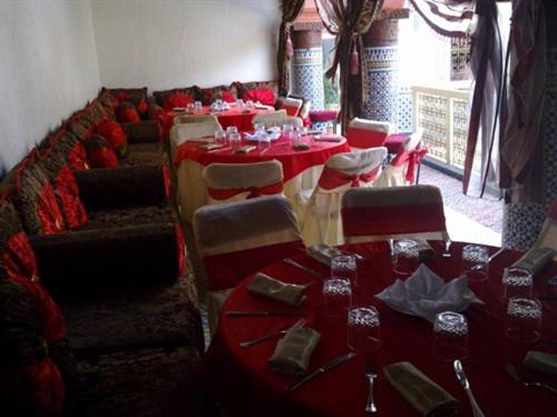 une salle avec des tables, des chaises et un tissu de table rouge dans l'établissement Riad Azrou, à Azrou