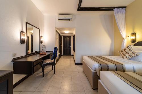 a hotel room with a bedroom with a desk and a bed at PrideInn Flamingo Beach Resort & Spa Mombasa in Mombasa