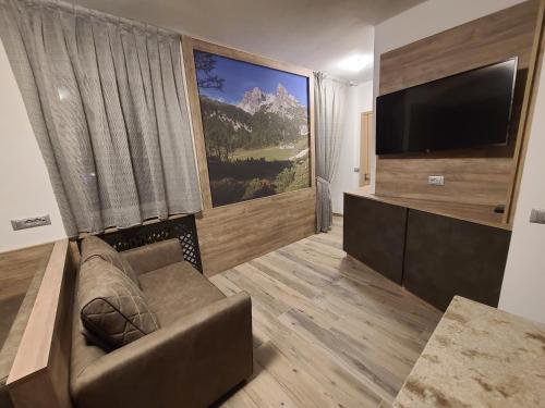 ein Wohnzimmer mit einem Sofa und einem Flachbild-TV in der Unterkunft Al Toscana in Andalo