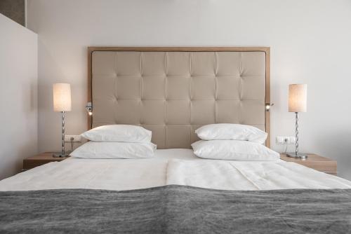 a bedroom with a large white bed with two lamps at ALPIANA - green luxury Dolce Vita Hotel in Vollan