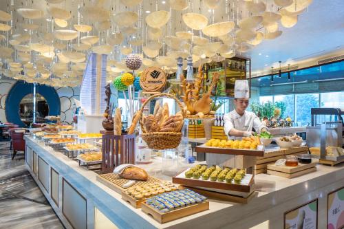 a chef standing behind a counter in a bakery at Wyndham Grand Foshan Gaoming in Gaoming