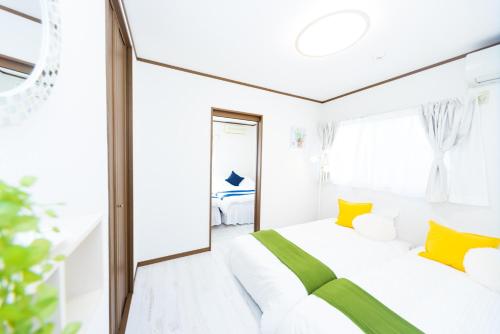 a white bedroom with yellow pillows and a large window at Awaji Garden House in Shinmura in Sumoto