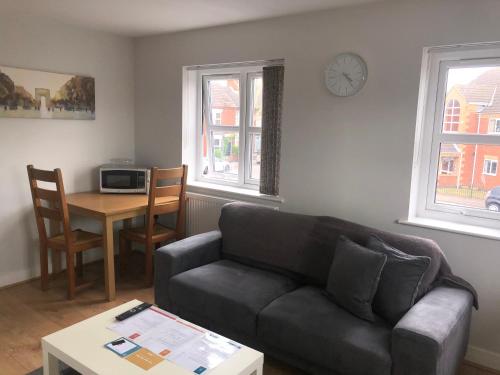 a living room with a couch and a table and a clock at Large 1st Floor Open Plan Apartment in Loughborough