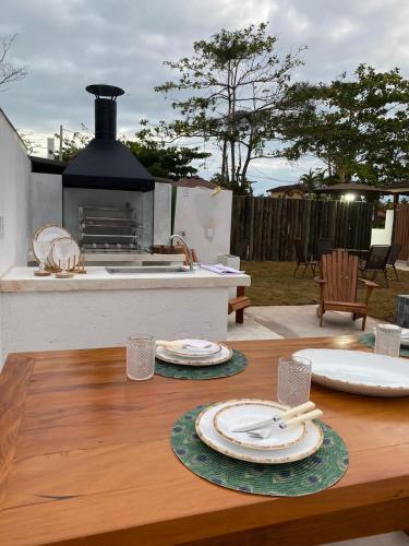 a wooden table with plates and utensils on top of it at Flat Pitaya - Cond. Morada da Praia in Bertioga