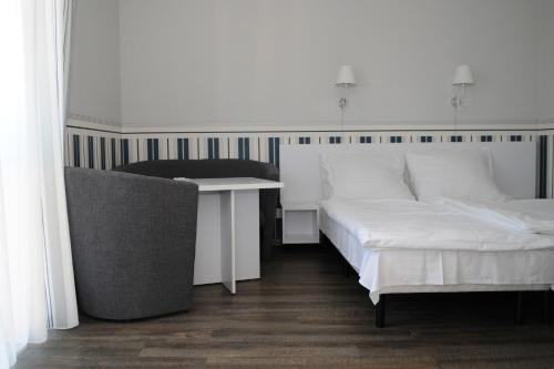 a bedroom with a bed and a desk and a chair at Pension Villa Karmelia in Darlowko