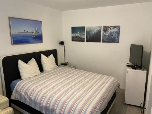 um quarto com uma cama com televisão e fotografias na parede em Apartment im Herzen von Bremgarten em Bremgarten
