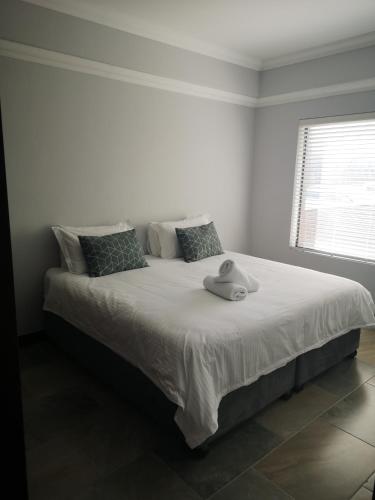 een witte slaapkamer met een bed met een hoed erop bij 208 Coral Reef in La Mercy