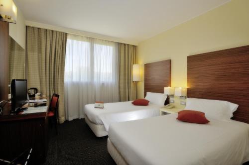 a hotel room with two beds and a desk at La Meridiana Bleisure Hotel in Perugia