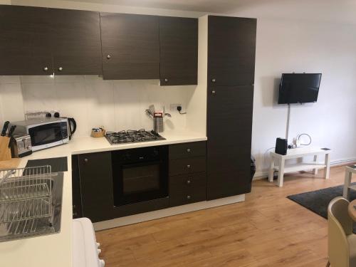 cocina con armarios negros y horno con fogones en 2 Bedroom Large First Floor Apartment with FREE Parking, en Loughborough