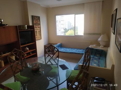 ein Wohnzimmer mit Tisch und Stühlen und einem Fenster in der Unterkunft Apto a 25 metros areia PITANGUEIRAS Vista mar 4 quartos 3 banheiros 1 vaga carro Serviço de praia in Guarujá