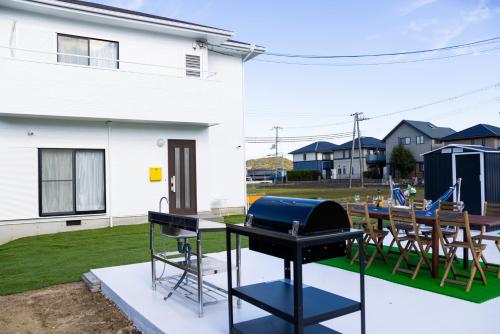 a grill on a patio with a table and chairs at Awaji Garden House in Shinmura in Sumoto