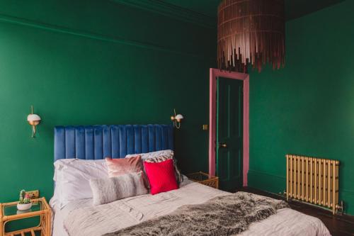 a bedroom with green walls and a bed with red pillows at Ballarat House in Margate