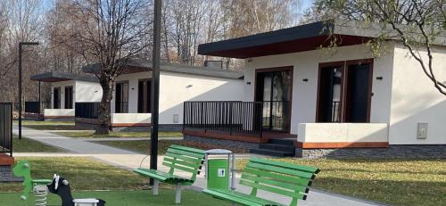 two green benches in front of a building at WRZOS resort & wellness **** DOMKI CAŁOROCZNE in Węgierska Górka