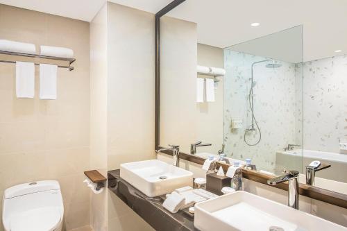 a bathroom with a toilet and a sink and a mirror at Swiss-Belhotel Cendrawasih, Biak in Fandoi