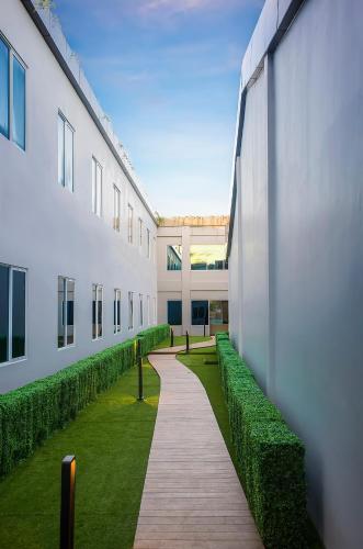 a walkway between two buildings with green plants at Swiss-Belhotel Cendrawasih, Biak in Fandoi
