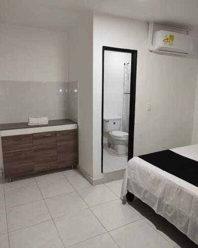 a bedroom with a bed and a bathroom with a toilet at HOTEL BLACK & WHITE in Cali